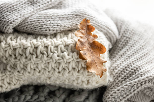 istock Close-up of a stack of knitted sweaters with autumn leaves. 1725603956