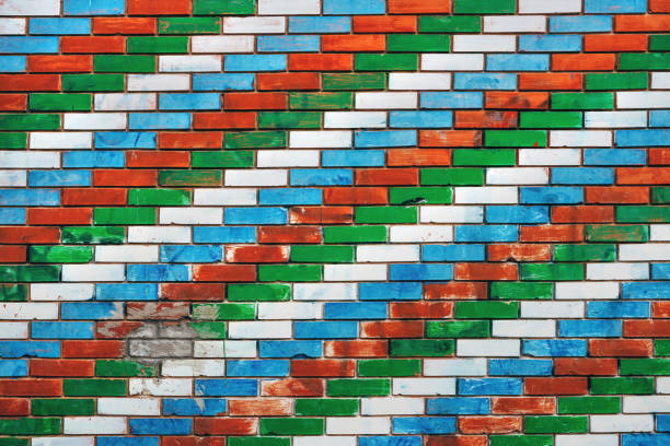 Colorful brick wall with diagonal pattern with white, blue, red and green colors, worn facade