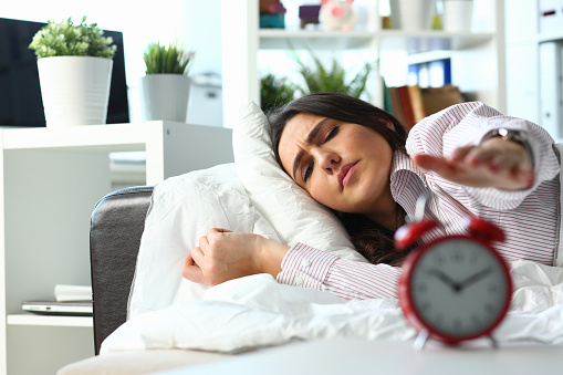 Worried dissatisfied annoyed dissatisfied young woman lying in bed. Turn off alarm clock spend time in bedroom