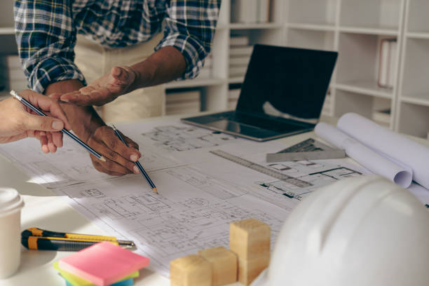 istock Architect, design engineer working on blueprint planning Group of construction engineers pointing at building on blueprint and using laptop to draw building design project Close-up pictures 1725628173