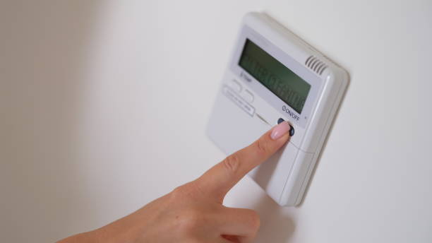 istock Female hand presses air conditioner button on wall closeup 1725629318