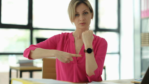 Business manager points to the clock at workplace. Time management and time planning