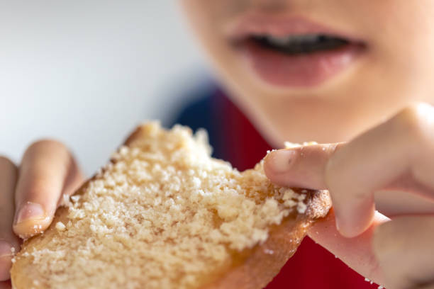 istock A child eats bread with grated cheese, close-up. 1725638282