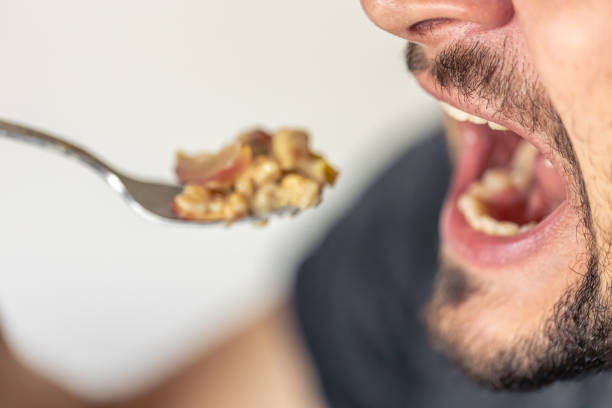 istock A man eats porridge with fruit, the man's mouth is open. 1725646235