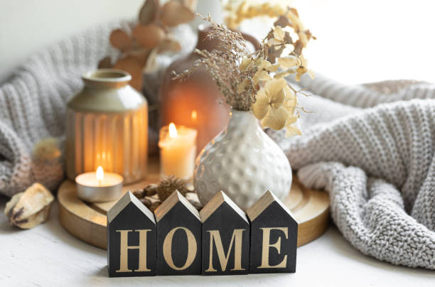 istock A cozy composition with the wooden word Home, candles and a knitted element. 1725656483