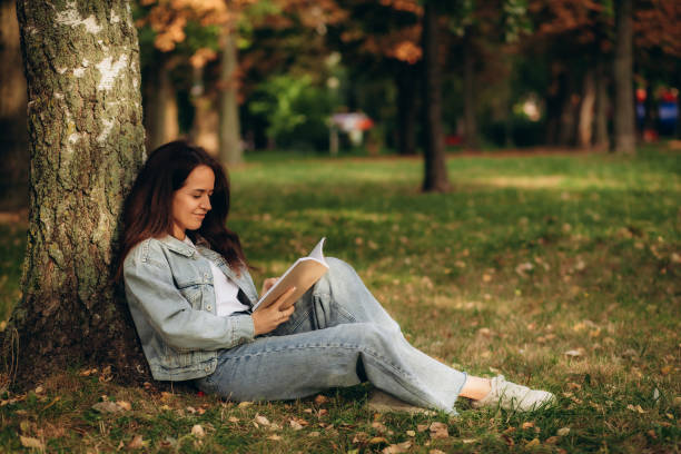 istock Young woman reading book under the tree during picnic in evening sunlight 1725657123