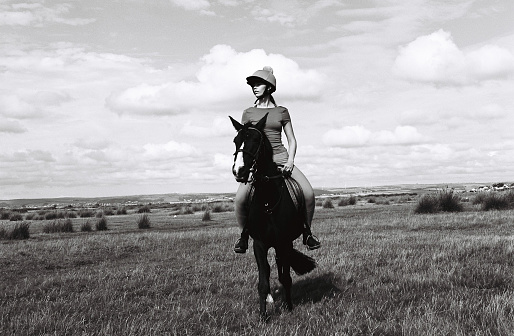 Ayoung woman rides a horse across fields, 34mm black and white film, Devon UK.