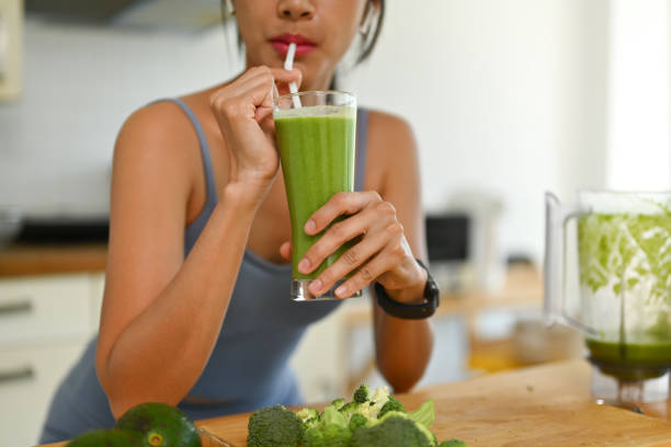 朝のトレーニングの後に緑の野菜のスムージーを飲むスポーツウェアの若い女性のショット - smoothie drinking women drink ストックフォトと画像