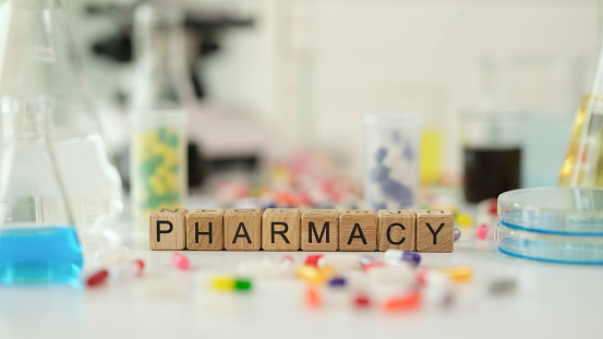 Word pharmacy with medical pills and microscope and laboratory glassware. Pharmaceutical research and medicine