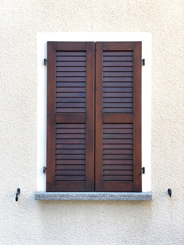 Closed wooden shutter on light lime wall