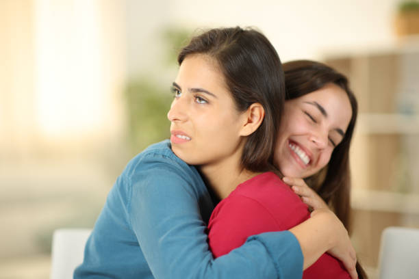 istock Happy woman hugging a false friend at home 1725681083