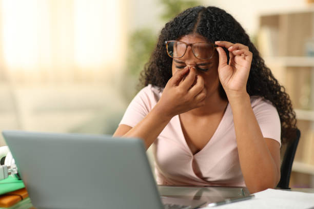 Black student suffering eyestrain studying at home