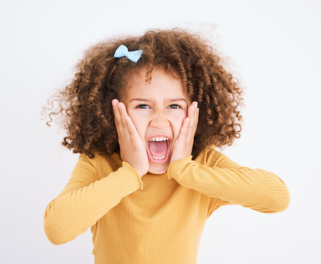Child, hands on face and scream in studio for fear, bad news or announcement for horror or anxiety. Portrait of a young girl isolated on a white background and shouting while scared, terror or angry