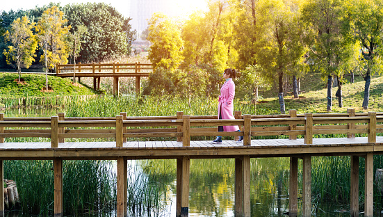 Woman walking on wooden bridge in public park.