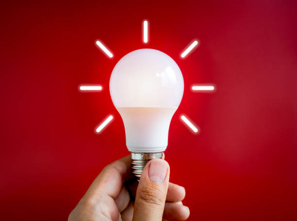 istock Glowing white light bulb with graphic radius neon style, holding by hand isolated on dark red background. Close-up creative lightbulb in creator's hand, inspiration and idea concepts. 1725734573