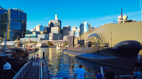 Maritime Museum, Darling Harbour, Australia - June 09 2019 : A submarine docks as visitors admires the breathtaking views overlooking the Sydney skyscrapers on a warm afternoon.
