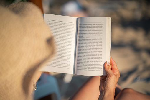 Close-up of unrecognizable woman reading a book at the beach