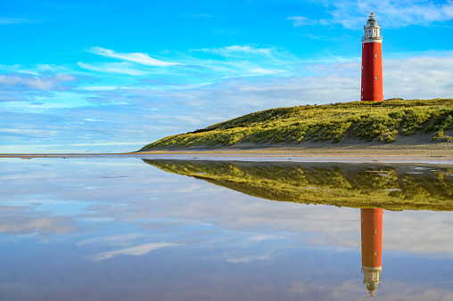 Lighthouse at the Wadden island Texel in the dunes during a calm autumn afternoon with reflections on the North Sea beach. The Eierland lighthouse is located at the North point of the island.
