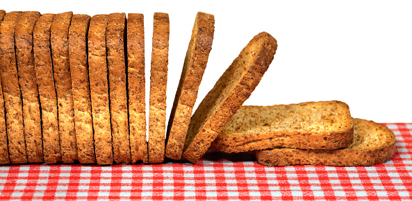 Close-up of a row of a group of rusks above a table with a red and white checkered tablecloth, isolated on white background.