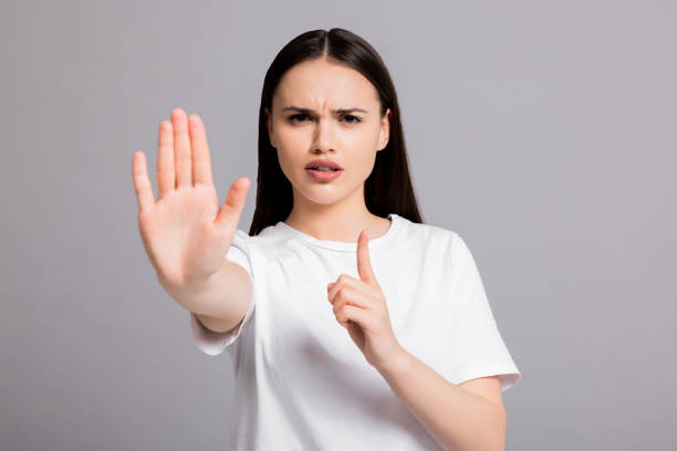 istock Angry young woman in white casual basic t-shirt standing on grey background isolated shwoing stop gesture at camera 1725802437