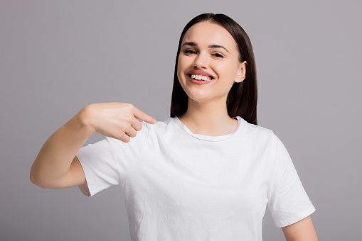 Portrait of adorable delighetd woman pointing index finger herself impressed she choose news wear good look white asic casua t-shirt isolated over grey background.