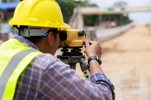 Close up Engineer use theodolite equipment for route surveying to build a bridge across the intersection to reduce traffic congestion during rush hours.