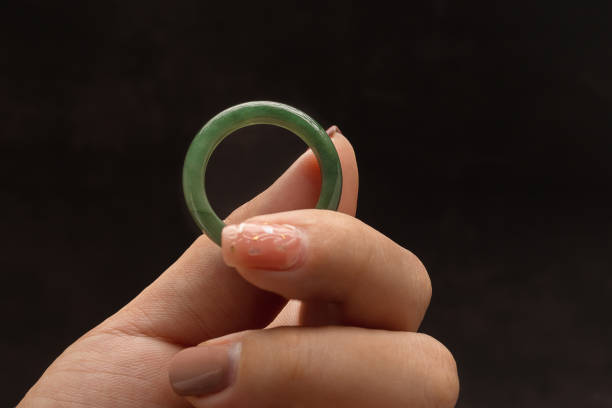 istock Hand holding of a green jade ring on a black background 1725823100