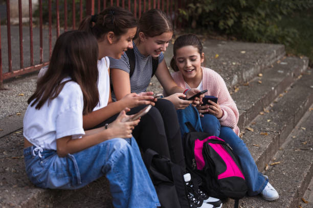 istock School girls sitting on staircase and using smart phones 1725831108