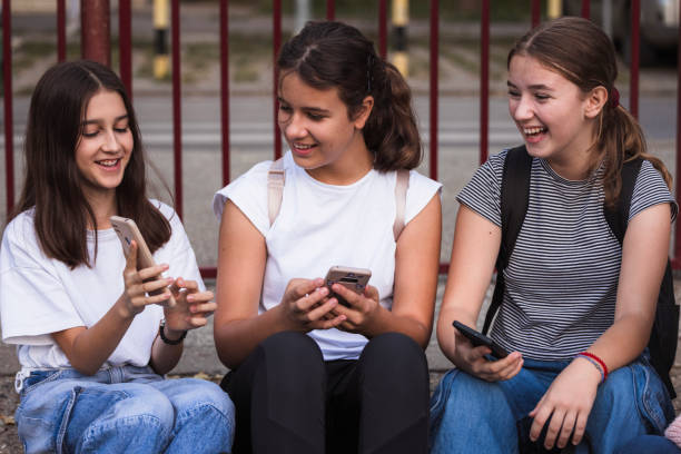 istock Happy school friends using phones and relaxing on a staircase 1725832002