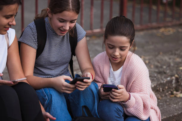 istock Happy school friends using phones and relaxing on a staircase 1725832023