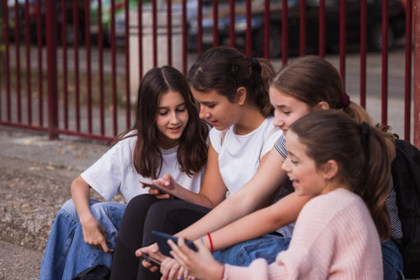 istock Happy school friends using phones and relaxing on a staircase 1725833736