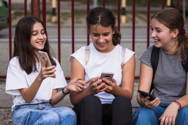 istock Happy school friends using phones and relaxing on a staircase 1725833757