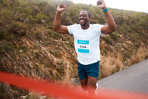 Black man, winner of race and fitness with cheers, athlete and sports with running in street and competition. Marathon, winning and celebration with African runner, happy champion and success outdoor