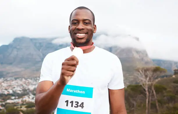 Photo of Runner man, winner and medal in portrait for marathon, competition or race with smile in Cape Town. African athlete guy, champion and success in challenge, contest and happy for metal prize in nature