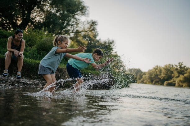 Young boy and girl playing together in the shallow part of river in nature.