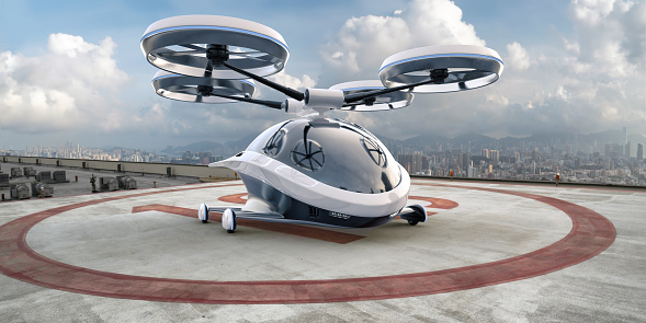 A generic white and grey eVTOL vehicle with blue highlights parked on a helipad on the rooftop of a high buildings in a downtown district with view of high rise city buildings in the background, under a bright sky with white clouds.
