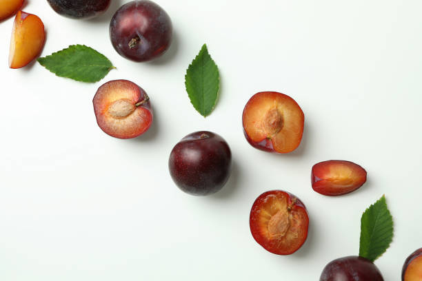 istock Tasty plums with leaves on white background 1725912980