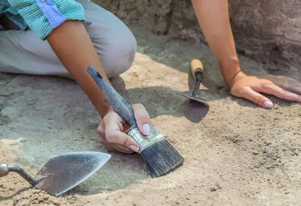 Photo of Professional Archaeological excavations, archaeologists work, dig up an ancient clay artifact with special tools in soil