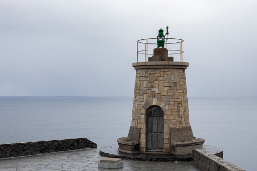 Lighthouse Overlooking Calm Sea Under Overcast Sky