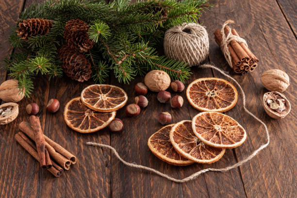 istock Christmas composition with dried orange slices, nuts, cinnamon sticks, green spruce branches. Rustic still life. 1725980979