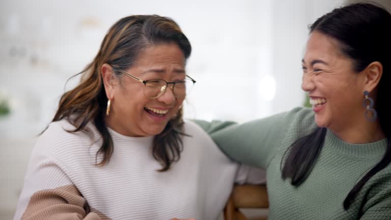 Laughing, talking and a mother with a daughter on the sofa for gossip, secret or conversation. Happy, funny and a senior mom speaking to a woman about a joke or comic story on a home couch together