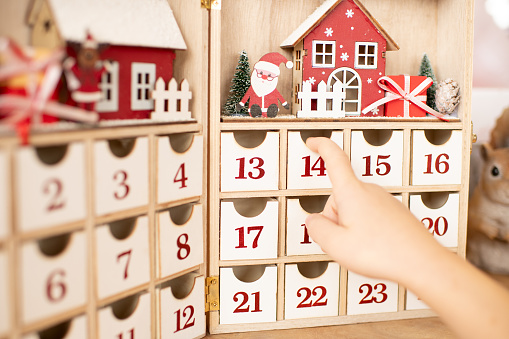 Hand of child opens wooden advent calendar