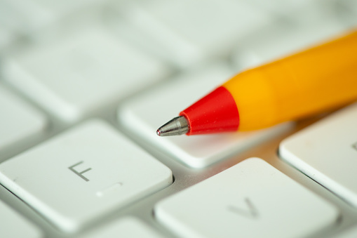 Close up of red and yellow pen on white keyboard