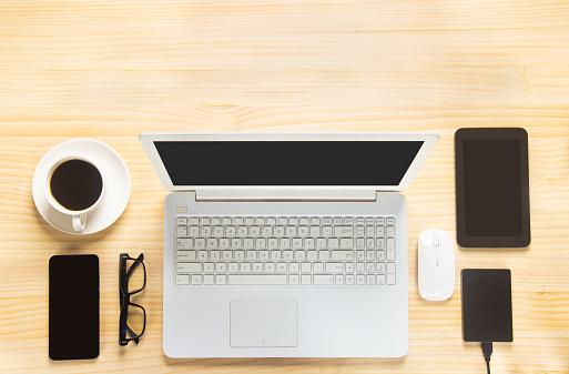 Home office desk with modern computer, coffee cup and houseplant.