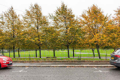Glasgow, Scotland - A parking space available on the street, with cars in front and behind the space on a road by Glasgow Green park.