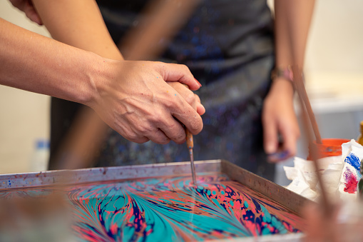 Oil-based inks in a tank of water being prepared for marbling. Paper marbling is a method of aqueous surface design.