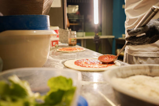 istock Spreading tomato on pizza dough - process of making pizza 1726114475