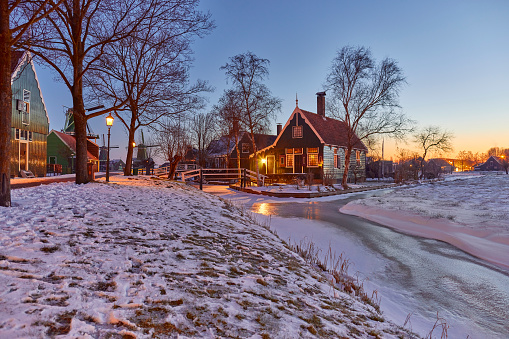 Zaanse Schans the historical village during winter, Netherlands. It’s early in the morning and the streetlights are still on. Everything is covered in snow.