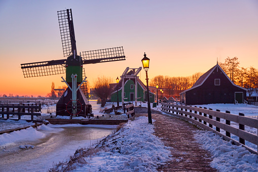 Zaanse Schans the historical village during winter, Netherlands. It’s early in the morning and the streetlights are still on. Everything is covered in snow.