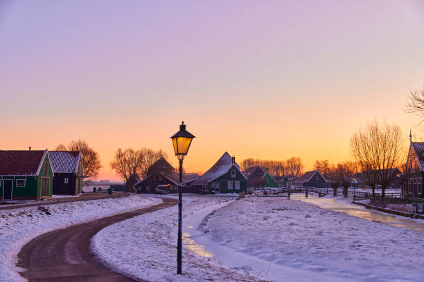Zaanse Schans the historical village during winter, Netherlands. It’s early in the morning and the streetlights are still on. Everything is covered in snow.
